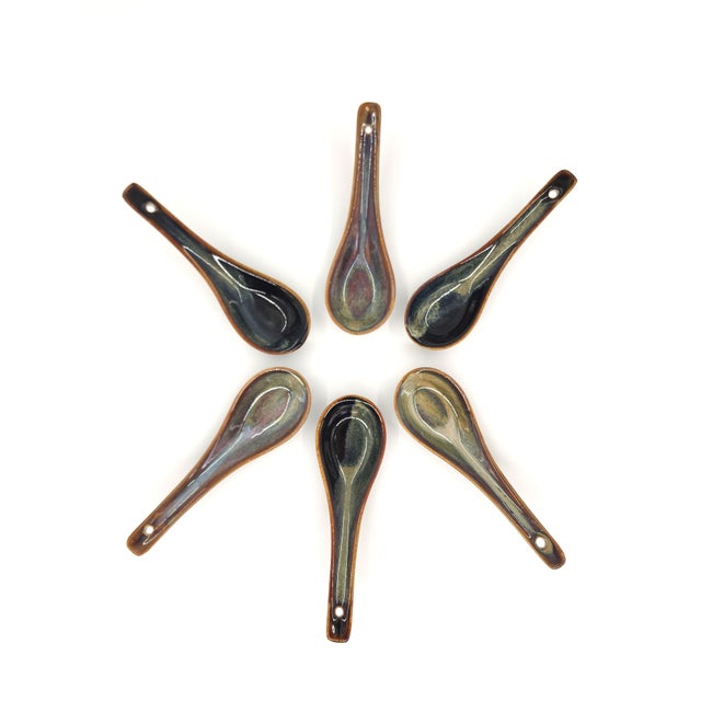 A beautiful set of six Asian-style ceramic soup spoons, featuring rich, variegated glazes in earthy tones of charcoal,...