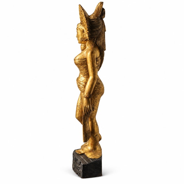 Elegant early 20th-century balinese female figure, hand-carved from dense tropical hardwood and richly finished with gold...