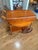 A wooden drop-leaf tea cart featuring an oval top with two folding side leaves, turned spindle legs, a lower shelf, and...