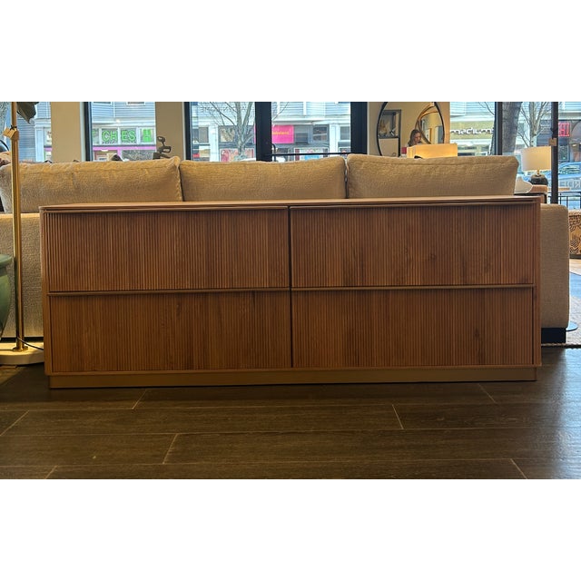 4-drawer lowboy dresser shown in rustic oak with flutted detailing and brass base. Curated by Arden Home. Unmarked Reg...