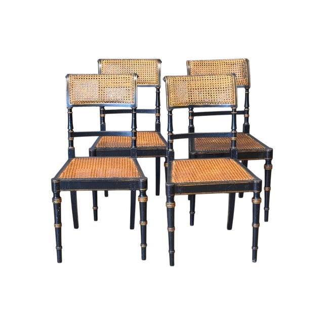 Ebonized frames with gilt line decoration throughout, each with a rectangular caned back panel, turned and gilt-banded...