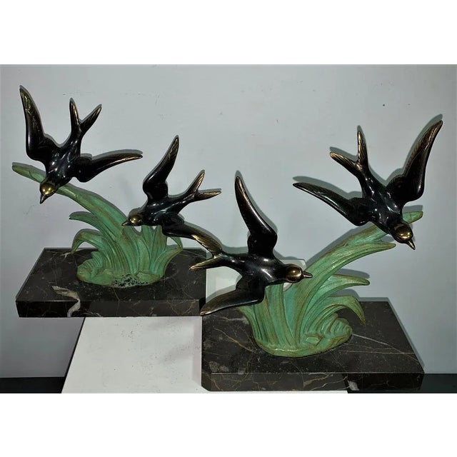 Pair of metal bird-shaped bookends on marble.