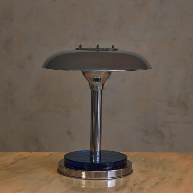 A French Art Deco table lamp in chrome and cobalt glass, dating to the 1950s. The wide domed shade rests lightly above a...