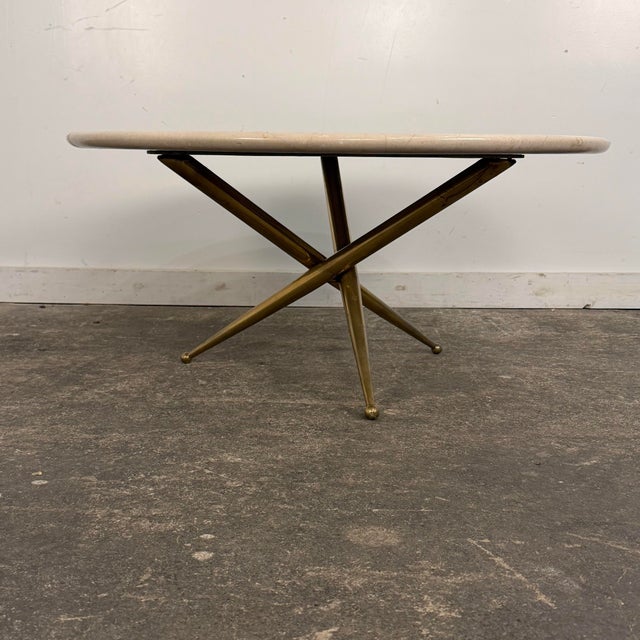 Elegant mid-century modern Italian table featuring a polished marble top set on a sculptural three-leg brass base. The...