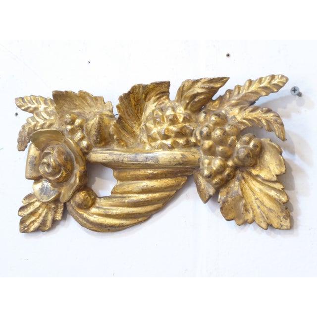 This carving of a cornucopia filled with fruits and wheat and flowers is goldleafed.