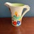 A striking and highly collectible Clarice Cliff daffodil shape jug in the sought-after “Secrets” pattern, dating to circa...