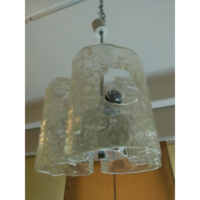 This three-lighted chandelier with a metal structure and structured glass diffusers was produced by Mazzega. This piece is...