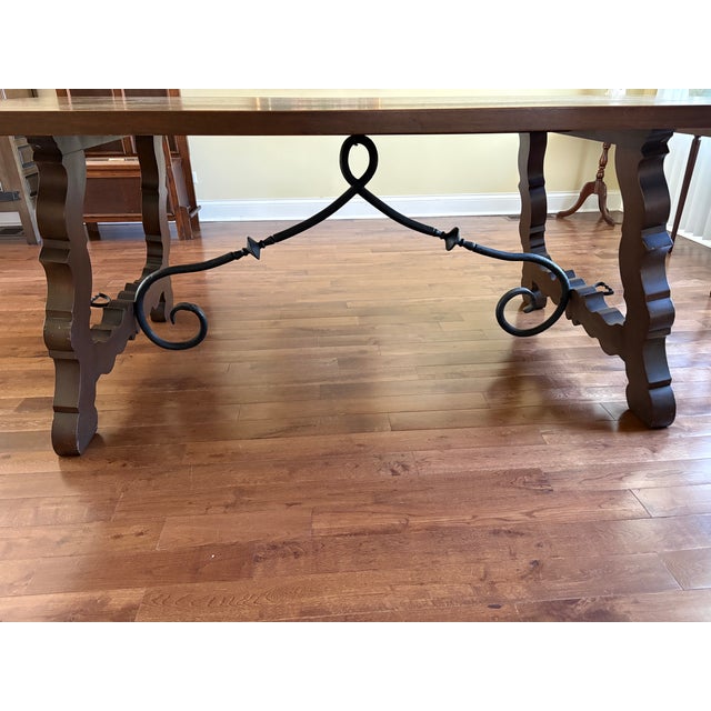 Elegant Spanish/Tuscan-style solid maple dining table with a striking curved iron stretcher base and substantial carved...