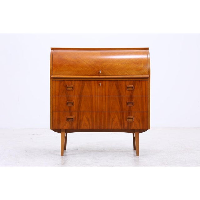 Vintage secretary desk with a classic roll-top and clean mid-century design. Behind the roll-top is a neatly organized...