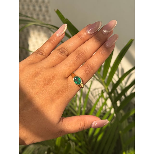 This bold 1.91 carat oval cut emerald signet-style ring is crafted in 18K yellow gold. The emerald measuring about 7.5 x 9...