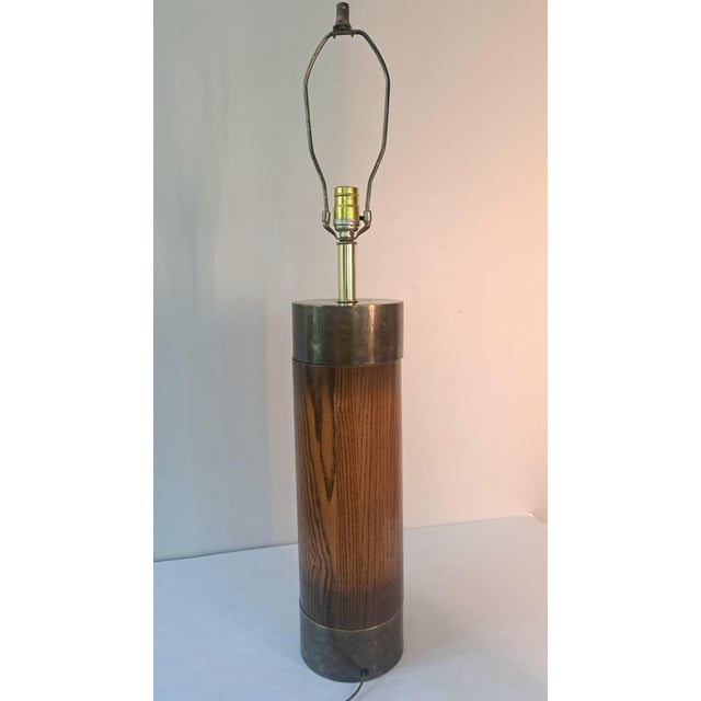A handsome vintage Mid-Century Modern table lamp with a streamlined cylindrical oak body framed by brass-tone metal bands....