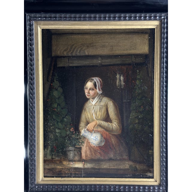 Charming 18th-century Northern European oil on panel depicting a young Dutch woman watering a plant from a blue-and-white...