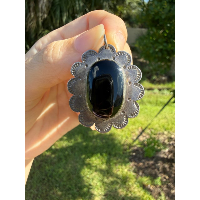 A striking vintage Mexican sterling silver pendant featuring a polished black onyx cabochon set within a sculptural...