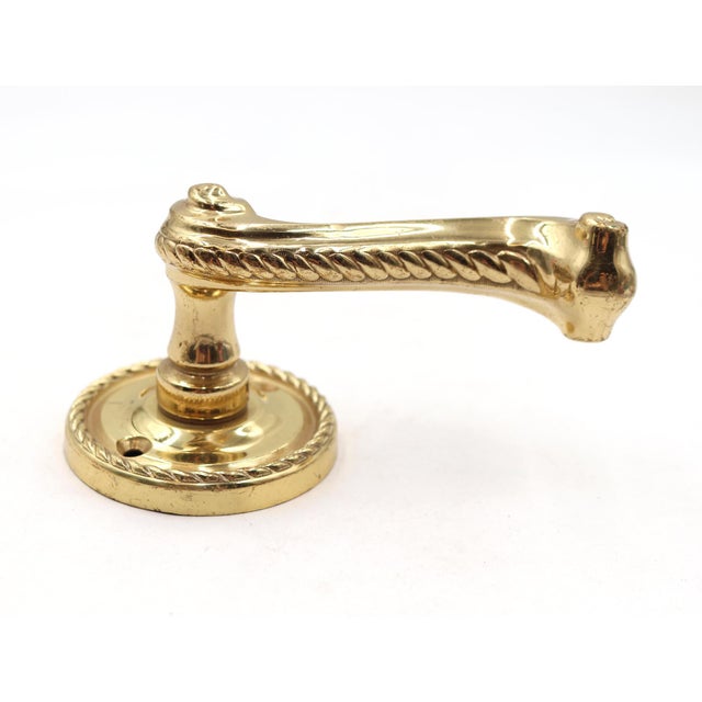 Modern brass braided door lever paired with a round rosette. The original rosette mounting screws are not available. Good...