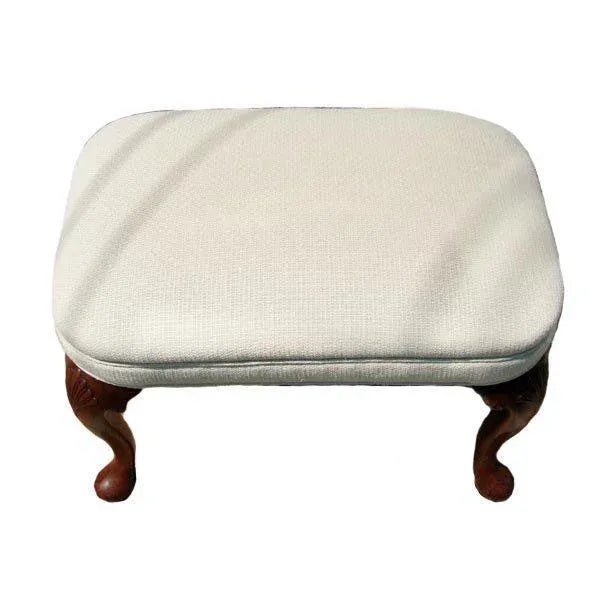 A fine Queen Anne style upholstered footstool with carved walnut legs. The legs are cabriole in form and have carved...