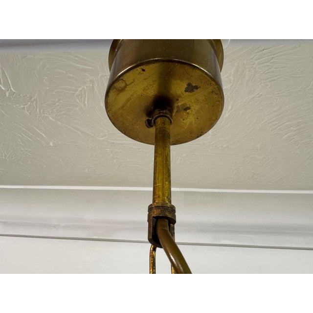 A 1960s Belgian pendant light featuring a deeply textured glass shade suspended from a patinated brass chain and ceiling...
