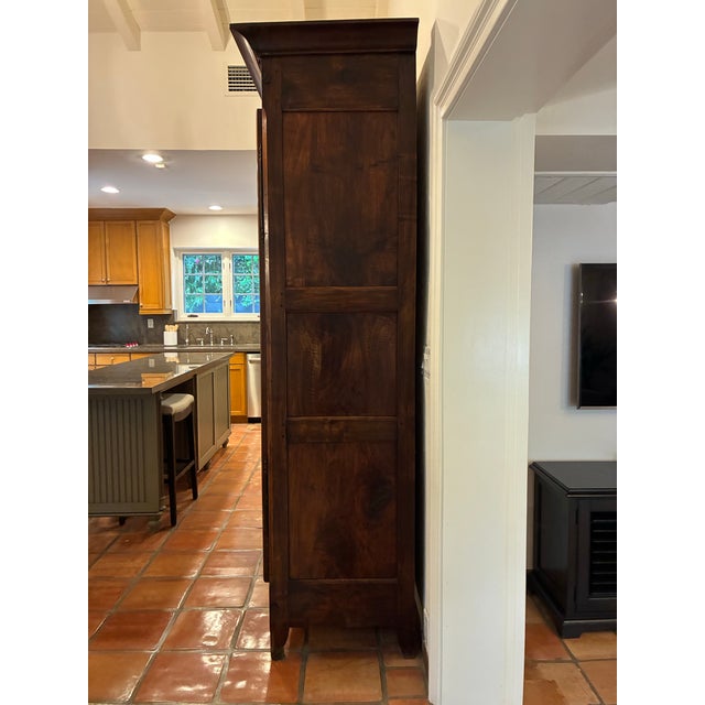 Impressive antique wood armoire with rich patina and paneled doors showcasing dramatic natural grain. Molded cornice above...