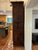 Impressive antique wood armoire with rich patina and paneled doors showcasing dramatic natural grain. Molded cornice above...