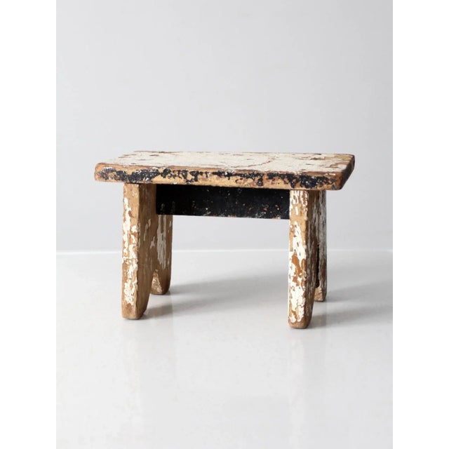 This is an antique wooden riser stool with a rustic farmhouse character. The solid wood stool features layered white and...