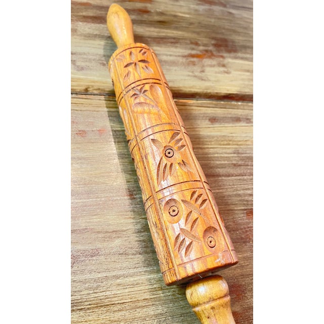 It is an embossing or molding rolling pin used to stamp intricate folk-art pictures—such as owls, birds, and floral...