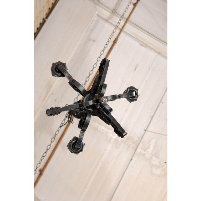 A French three-light iron chandelier from the mid 20th century. This vintage forged-iron chandelier from France features...