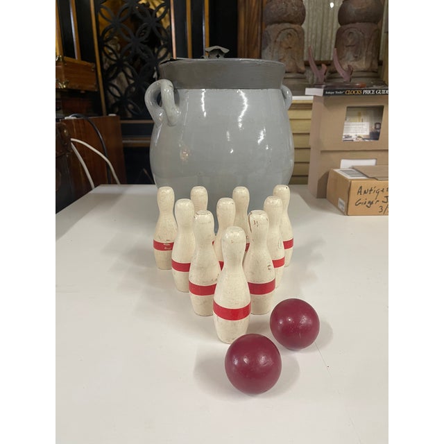 An antique hand painted table top bowling game set with nine white and red painted wooden pins and two red wooden balls....