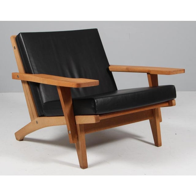Hans j. Wegner lounge chair with loose cushions new upholstered with black full grain aniline leather. Frame of oak. With...