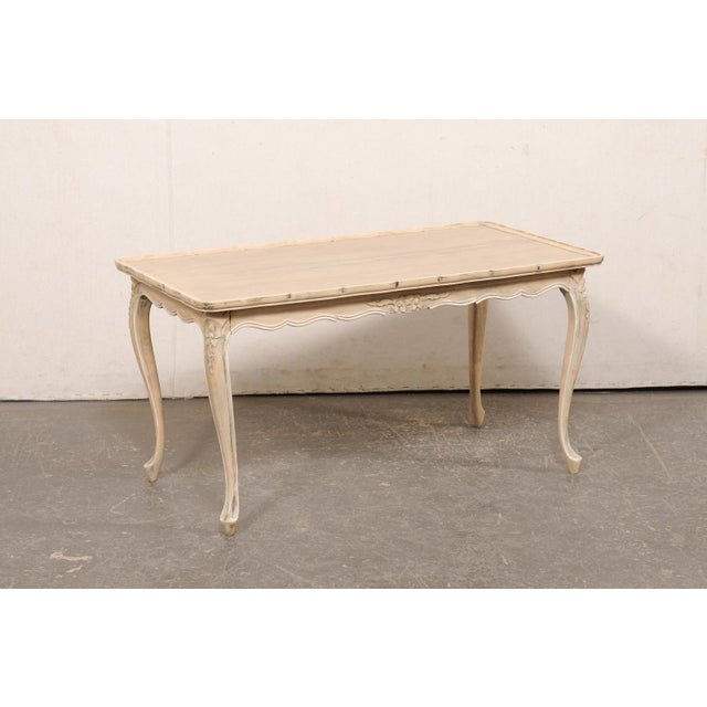 A French Louis XV style carved wood coffee table from the mid 20th century. This mid-century table from France is...