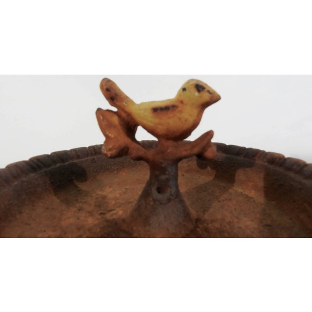 A chipper bird sits atop a branch in the centre of this miniature birdbath. It is made of cast iron that was finished in a...