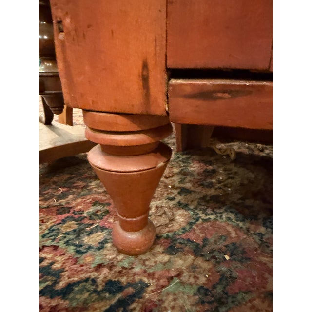 This primitive 19th century jelly cabinet features a rustic, red wash finish, an upper drawer and two doors opening to...