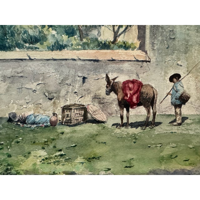 Original watercolor on paper depicting a rural village scene with a figure standing beside a donkey draped in red, baskets...