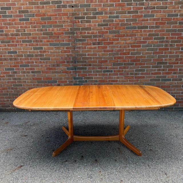 Danish Modern dining set featuring a solid teak dining table paired with four Model 85 dining chairs designed by Niels...