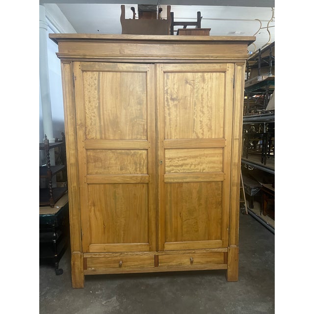 A large late 19th century European pine armoire or wardrobe in a warm honey-toned finish with a plain stepped cornice, two...