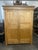 A large late 19th century European pine armoire or wardrobe in a warm honey-toned finish with a plain stepped cornice, two...