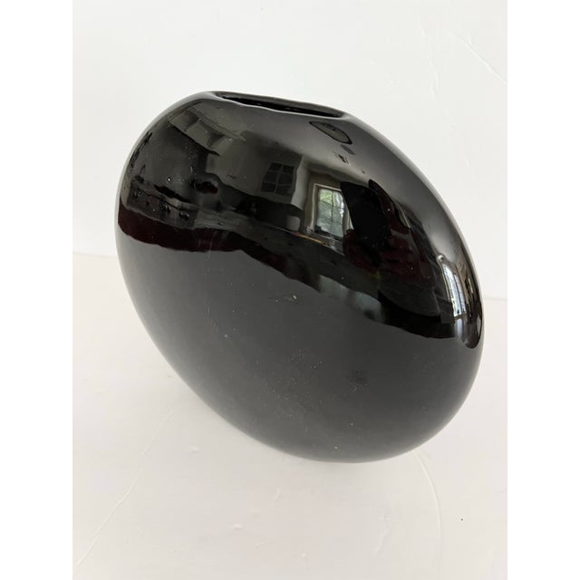 Love the style of this Mid-Mod Circular Flat Vase. Glazed in a shiny Black. Narrow opening at top. This piece retains its...