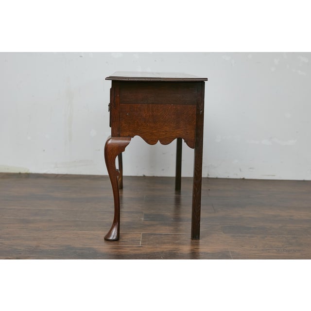 An English Georgian style two-toned oak server from the 19th century with drawers, carved apron and cabriole legs. This...