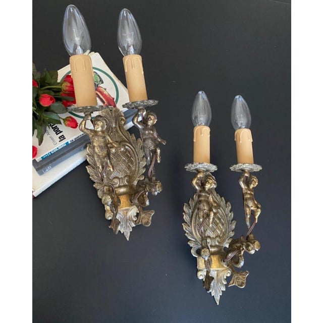 The sconces are made of bronze and brass Decorated with the famous Putti boy figurines and elegant forging Gorgeous...
