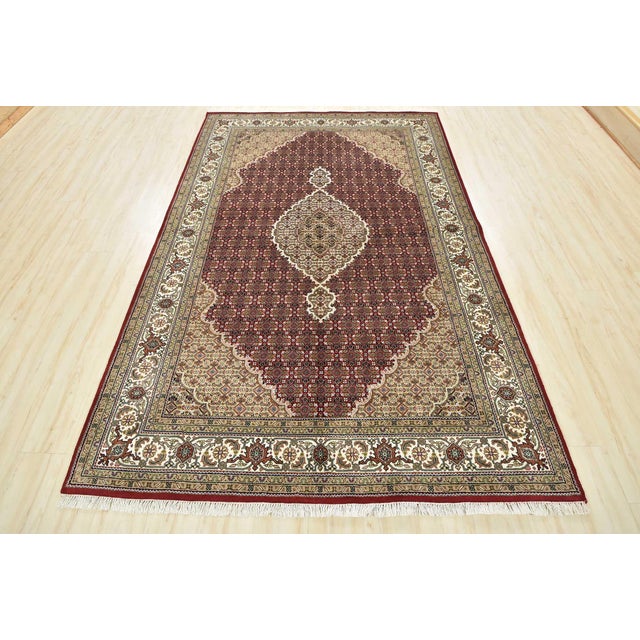 A traditional Tabriz Mahi rug hand-knotted with an all-wool pile on a cotton foundation. This finely woven oriental rug...
