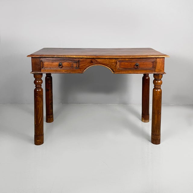 Italian Ethnic style modern desk in wood, 1980s Desk with a rectangular wooden top. Two drawers with metal handles are...