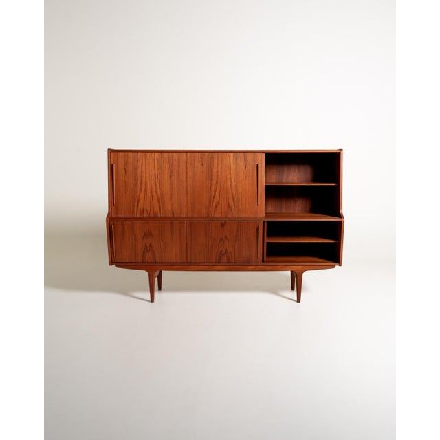 Danish teak tall sideboard from the 1960s, with sliding doors, three central drawers, and carved solid wood handles. The...