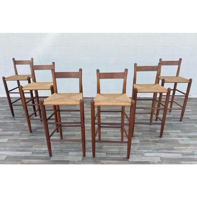 Beautiful vintage set of six Danish Modern style bar stools, circa 1970s, featuring solid wood frames with warm natural...
