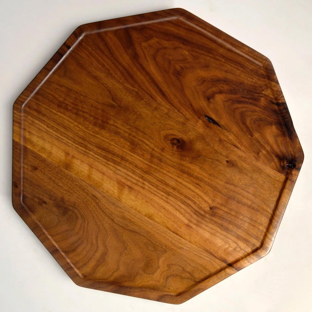 A handcrafted solid walnut nine-sided tray-top side table with a tripod base. The rimmed edge top is attached to a black...