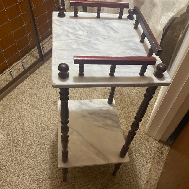 This is an antique two-tiered side table featuring white marble shelves with a mahogany spool turned legs.