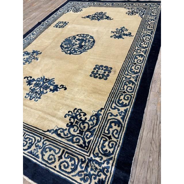 This late 19th or early 20th-century Chinese Peking rug features a serene, architectural design defined by a deep indigo...