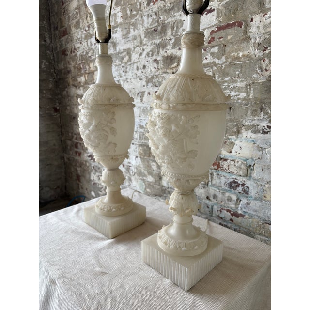 Impressive pair of vintage carved alabaster table lamps featuring substantial weight, richly detailed relief carving, and...