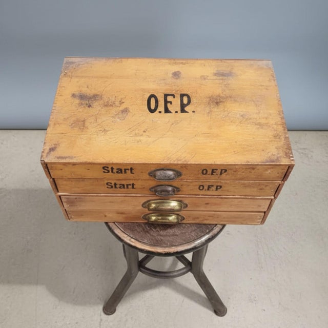 Authentic industrial wooden filing cabinet featuring four drawers with original brass cup handles. The upper drawers...