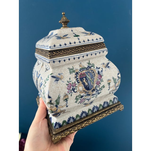 This exquisite lidded Capodimonte-style porcelain jar features finely detailed crest motifs, cherubs, birds, and floral...