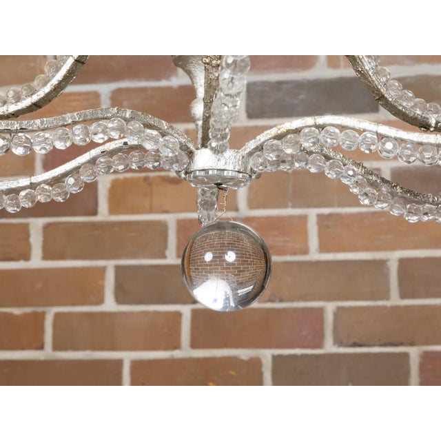 An Italian vintage crystal and steel chandelier from the 20th century with six scrolling arms. This exquisite Italian...
