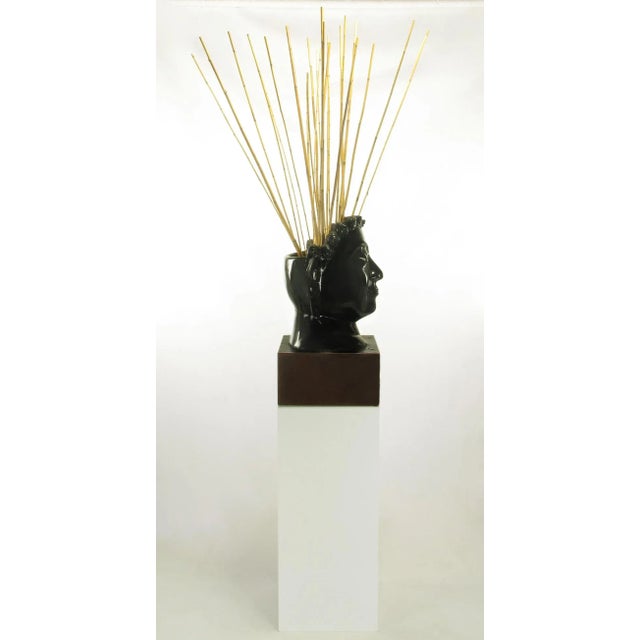 Carved and black lacquered mahogany bust of Buddha on mahogany plinth with white Lucite pedestal. The back of the head is...
