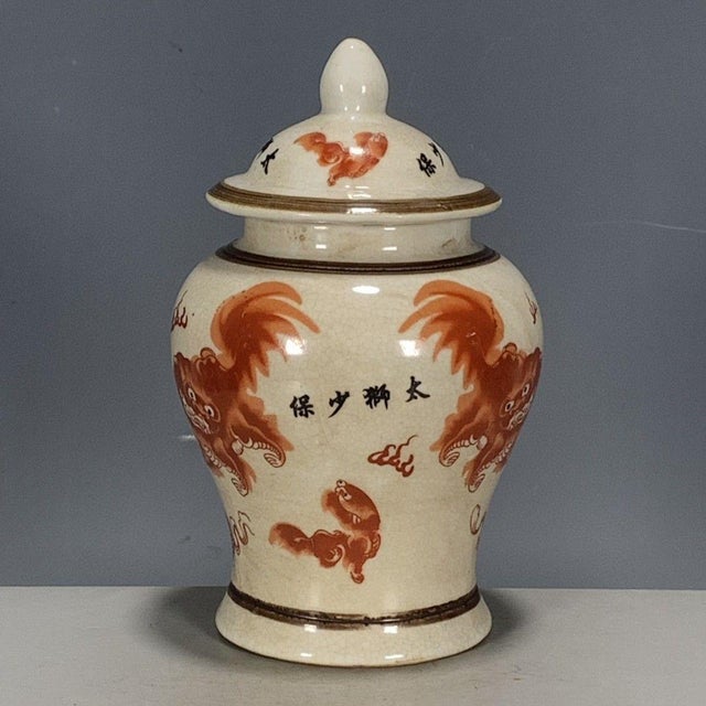 A charming Chinese porcelain covered jar featuring a creamy, all-over crackle glaze. The jar is decorated with iron-red...